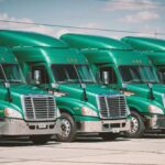 Groene vrachtwagens in een nette rij, toonbeeld van professioneel spuitwerk door een truckspuiterij